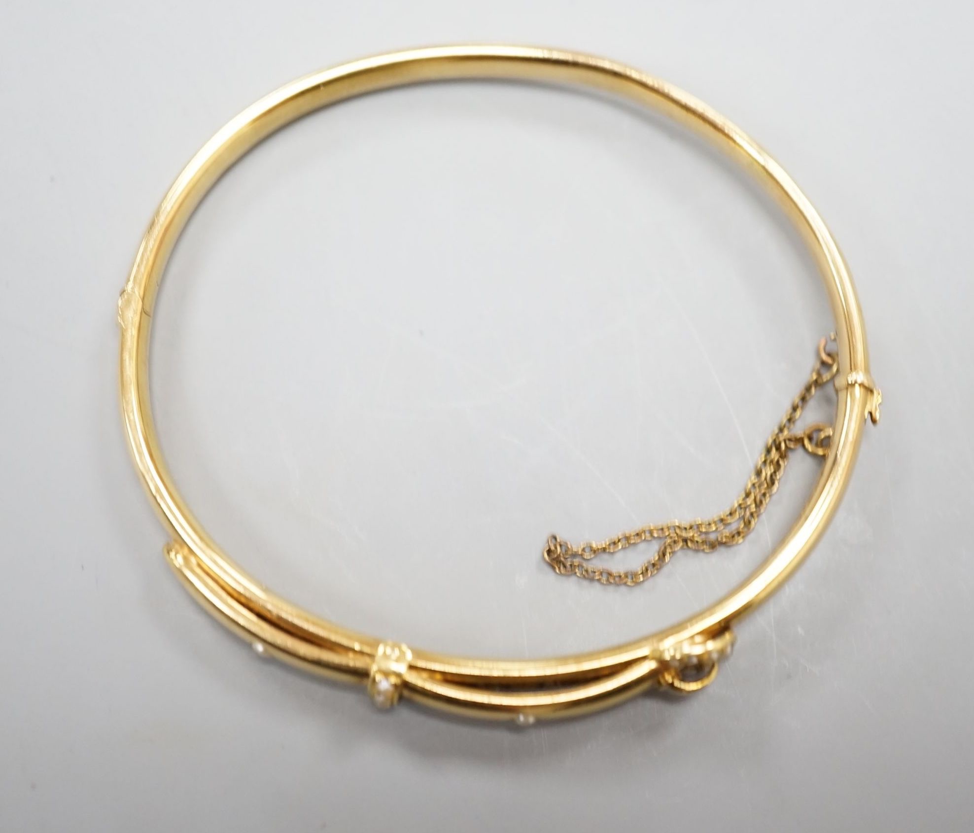 An Edwardian 15ct gold and seed pearl set hinged bracelet, interior diameter 58mm, gross weight 8.3 grams.